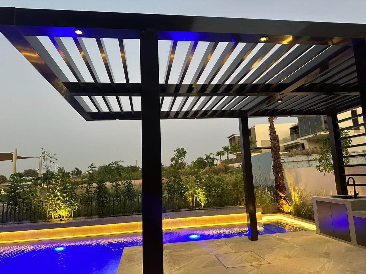 Aluminium pergola and outdoor kitchen beside a villa pool